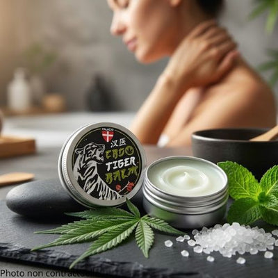  In the foreground, a small, round, vintage-style metal tin sits open on a smooth, dark slate stone, revealing a thick, white-mint-hued balm. Beside the tin, fresh green hemp leaves, a sprig of refreshing peppermint, and tiny white camphor crystals visually evoke the potency of the botanical ingredients.
